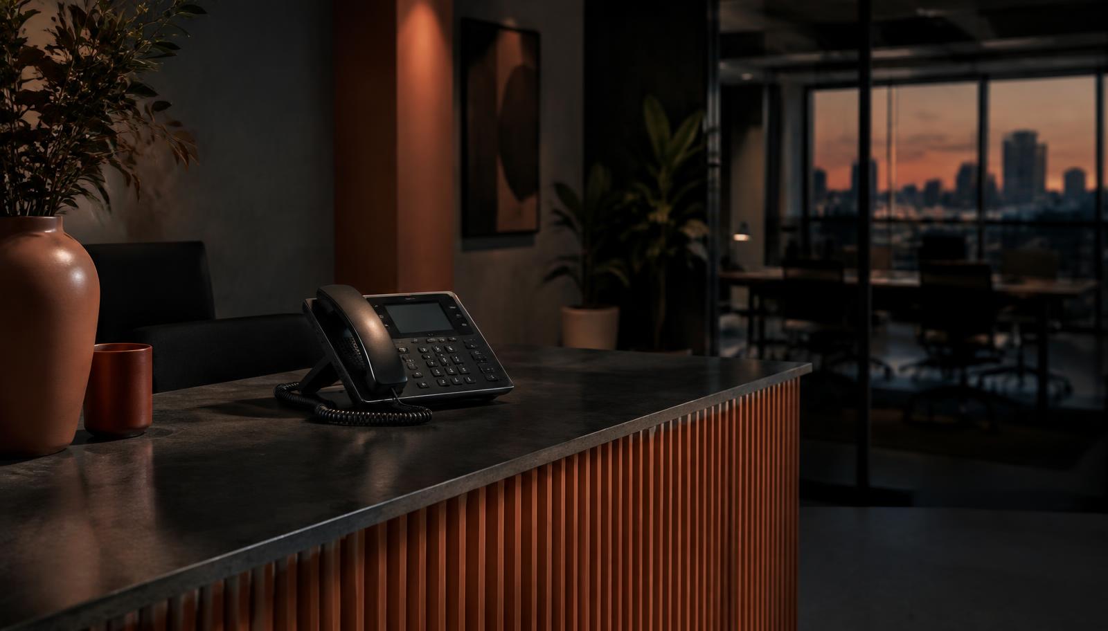 Unanswered desk phone and laptop showing an enquiry form in a quiet office