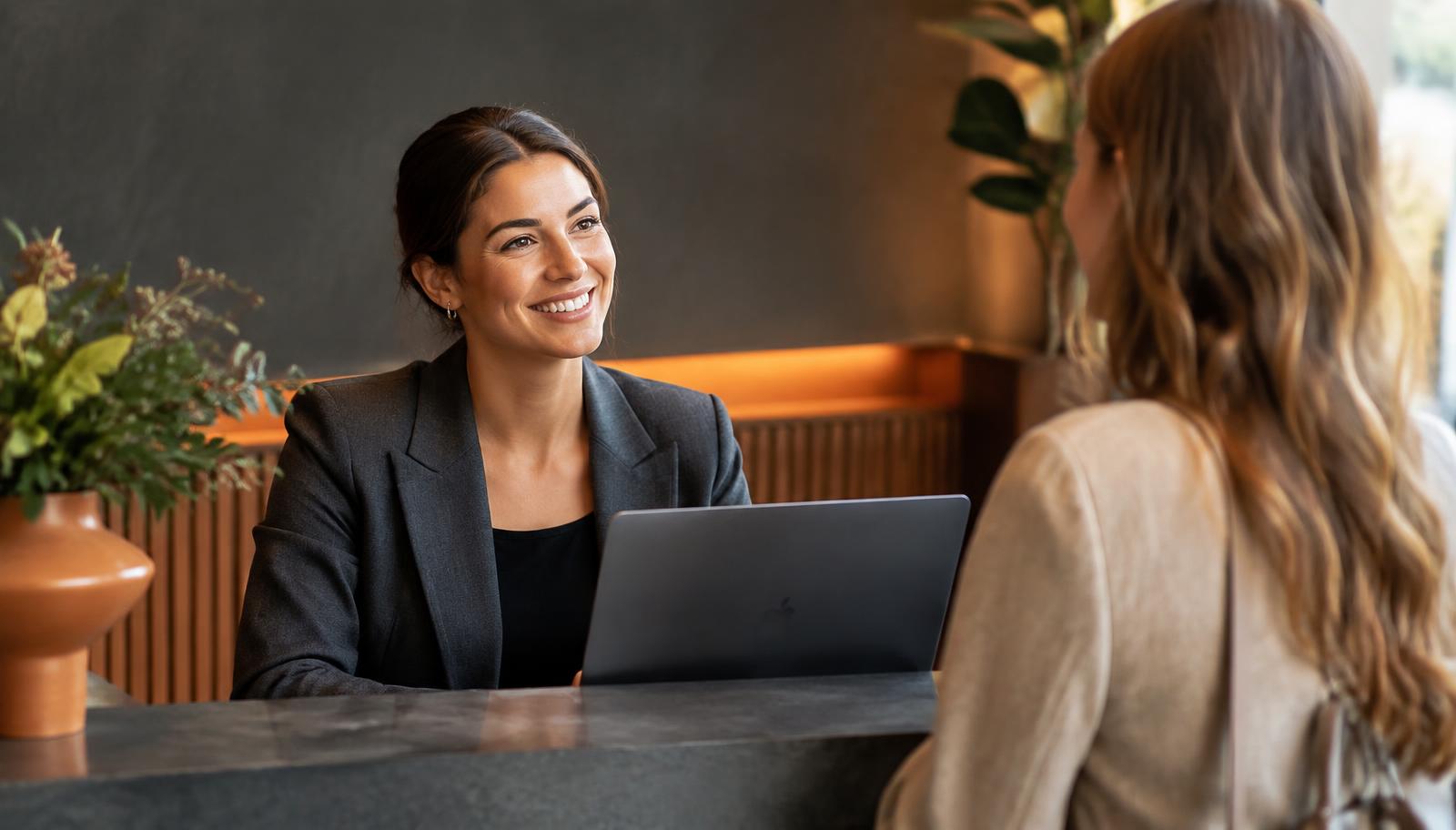Receptionist smiling while helping a customer at a modern reception counter